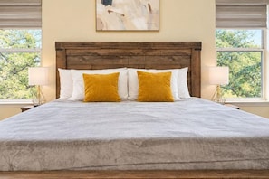 A large bed with a wooden headboard, two white pillows, and a mustard-colored accent pillow. - Beach-Entry Pool Mini-Golf FirePit SeaWorld & BMT (San Antonio)