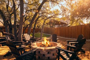 An outdoor seating area with Adirondack chairs, a fire pit, and a wooden fence. - Beach-Entry Pool Mini-Golf FirePit SeaWorld & BMT (San Antonio)