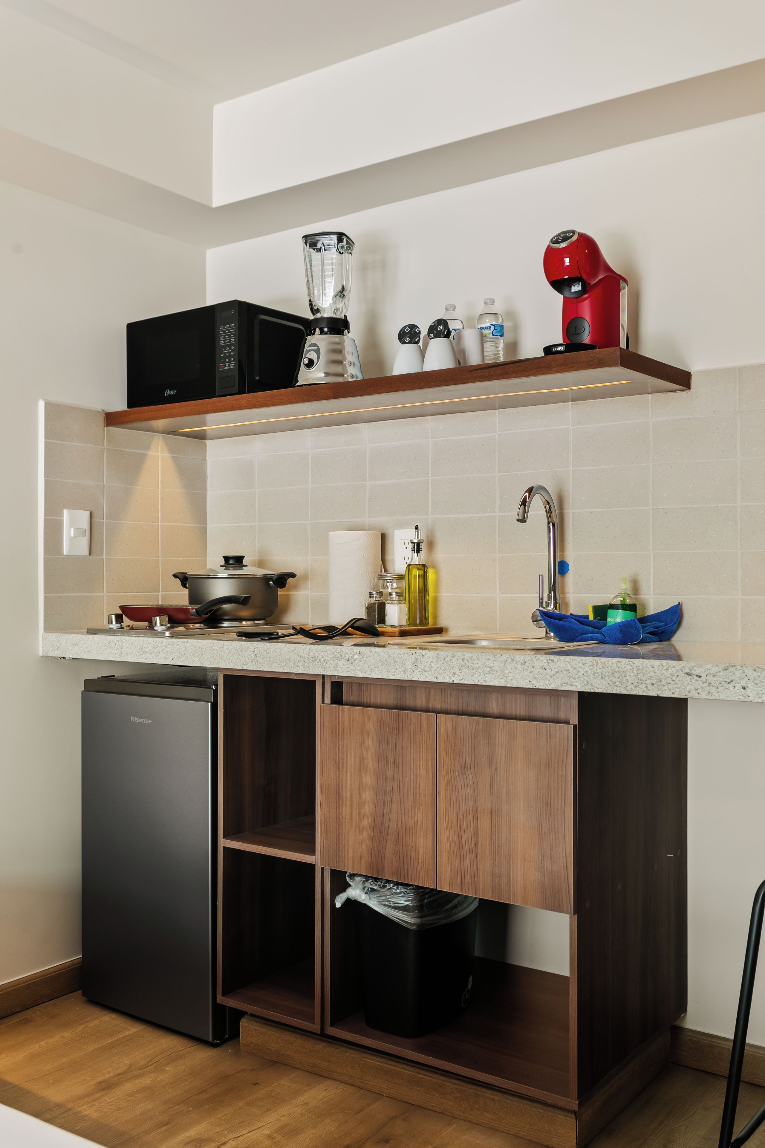 Una cocina funcional con lavavajillas integrado, estufa, pileta y encimera con licuadora y tetera.