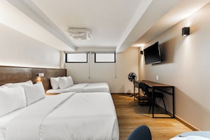 Habitación de hotel con dos camas, un escritorio, una silla, un televisor y un ventilador de techo.