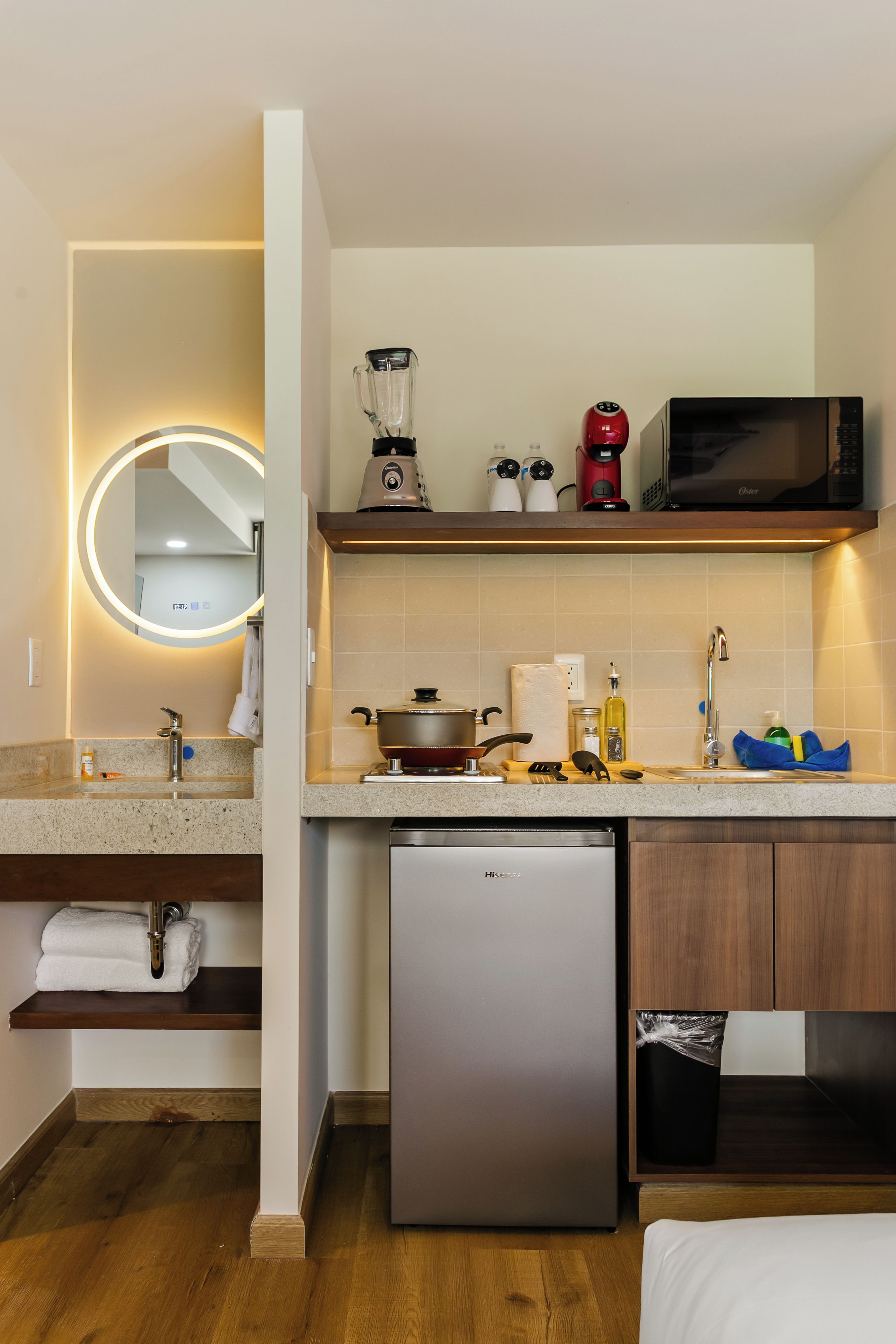 A compact kitchen with a built-in dishwasher, a microwave, a blender, and a kettle on the countertop.