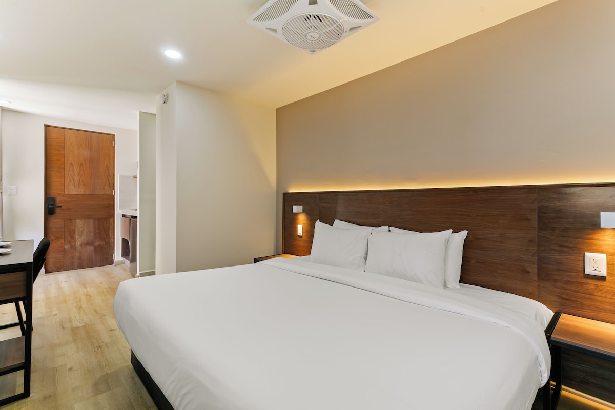 Una habitación de hotel con una cama grande, un escritorio y una puerta de madera.