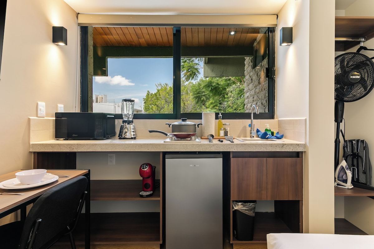 Cocina compacta con microondas integrado, refrigerador pequeño y ventana sobre el lavadero.