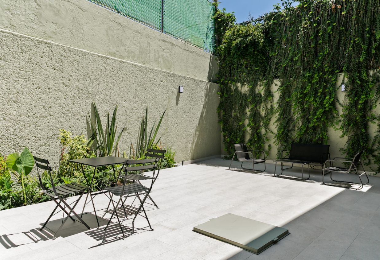 Eine Außenpatio mit Tisch und Stühlen, umgeben von Pflanzen und einer begrünten Wand.