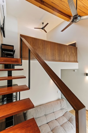 A modern interior with a wooden staircase leading to an upper level, a flat-screen TV mounted on the wall, and a ceiling fan. - Hierba By Homirent  (Santiago de Querétaro)
