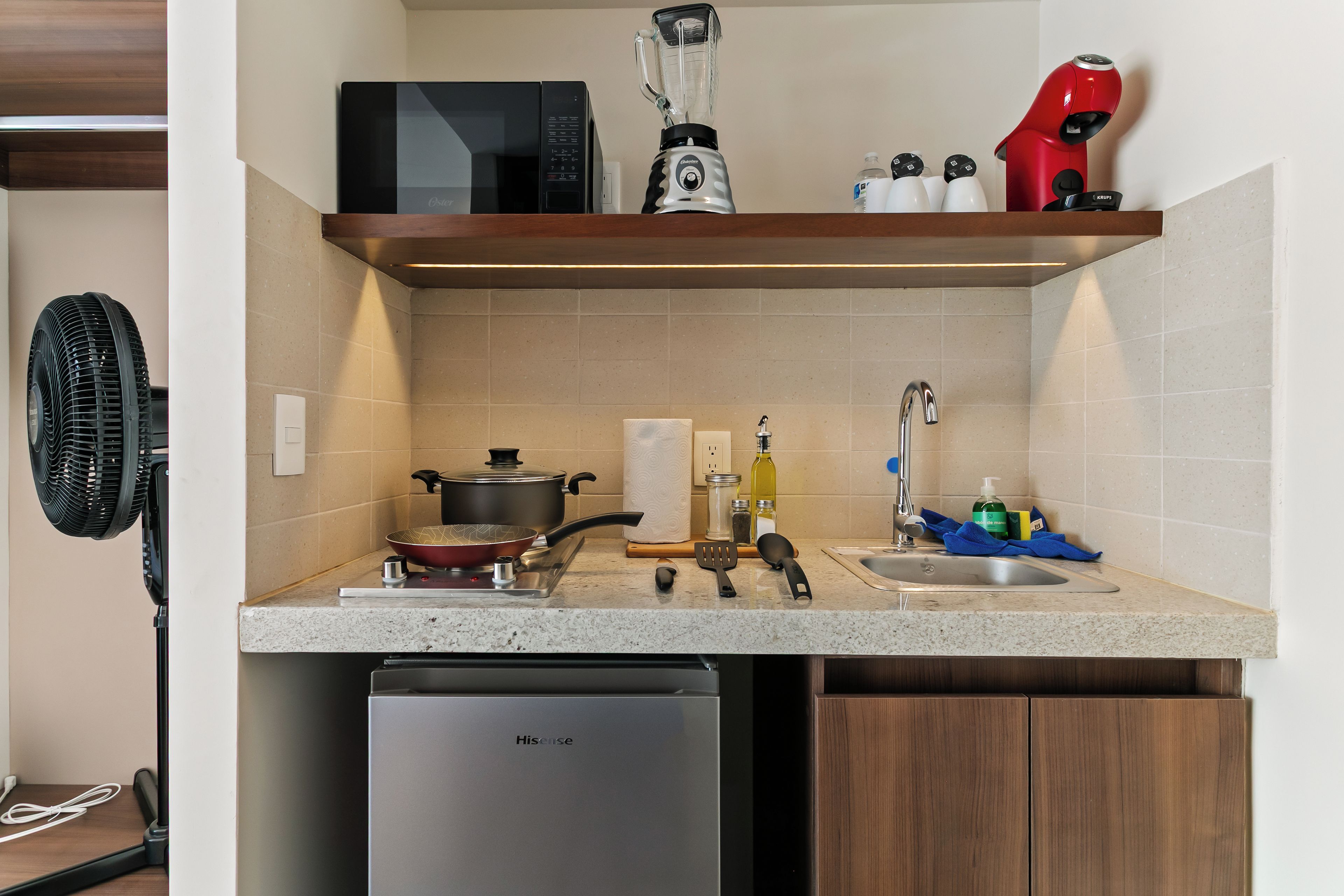 Cocina con microondas, licuadora y secador rojo en el estante, un lavabo con grifo y un lavavajillas.