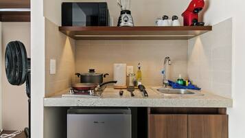 Cocina con microondas, licuadora y secador rojo en el estante, un lavabo con grifo y un lavavajillas.