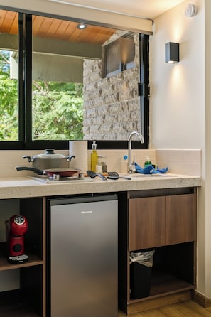 A compact kitchen with a built-in dishwasher, a small refrigerator, and a window above the sink. - Hierba By Homirent  (Santiago de Querétaro)
