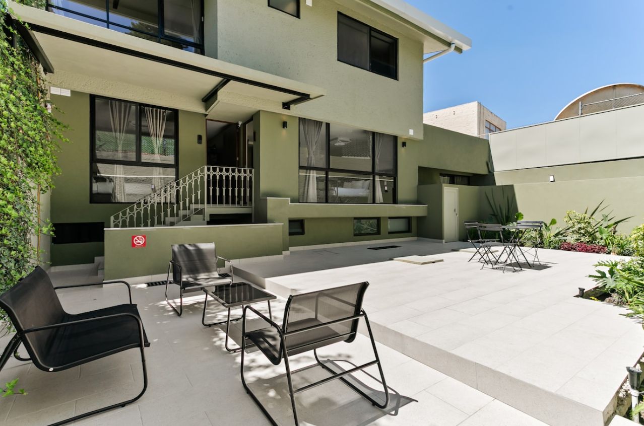Un bâtiment moderne doté d’un toit plat, de grandes fenêtres et d’un patio aménagé avec du mobilier d’extérieur.