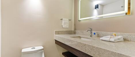 A bathroom with a toilet, sink, mirror, and towel rack.