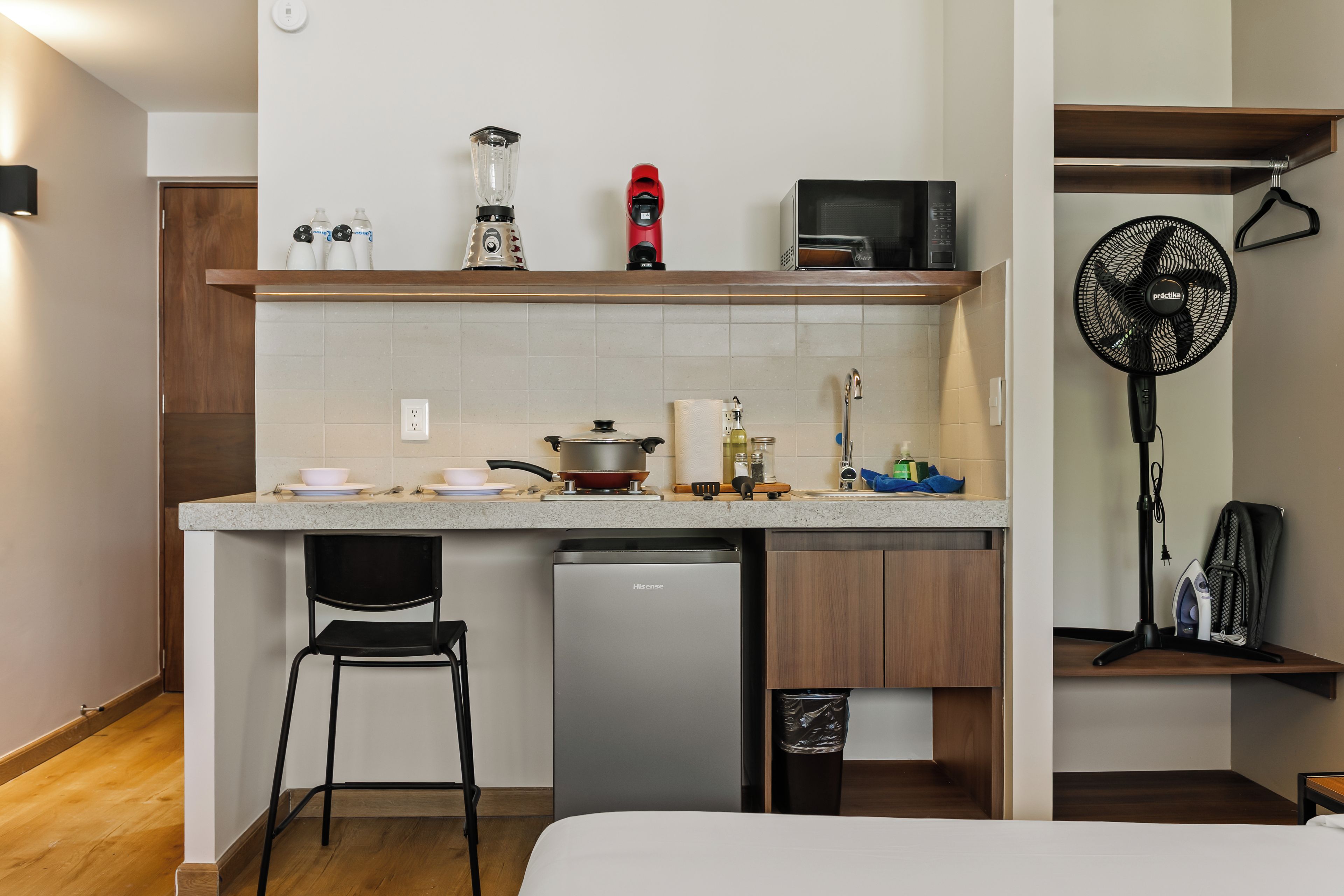A compact kitchenette with a built-in dishwasher, a microwave, a kettle, and a small stove.