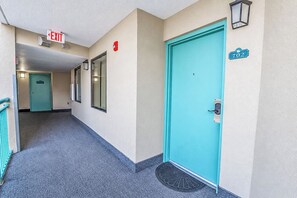 A hallway with a teal door, an exit sign, and a fire alarm. - Spacious 3BR Coastal Getaway at Sand Dunes (Myrtle Beach)