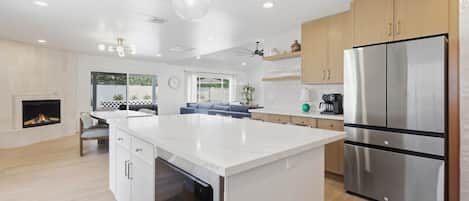 A modern kitchen with a central island, stainless steel appliances, and a fireplace.