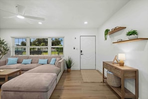 A modern living room with a sectional sofa, a wooden coffee table, a console table with a lamp, and a ceiling fan. - Pool Home | Fenced Yard | 9 Min to Beach (Venice)