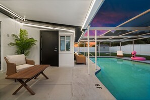 A covered outdoor area with a pool, a wooden table, and two wicker chairs. - Pool Home | Fenced Yard | 9 Min to Beach (Venice)