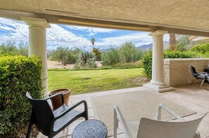 A covered patio with a view of a landscaped garden, outdoor furniture, and a stone wall. - Mesquite Mountain Retreat Phase 3 (Palm Springs)