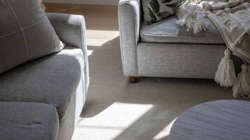 Un salon avec un canapé gris, un fauteuil assorti et une table basse ronde.