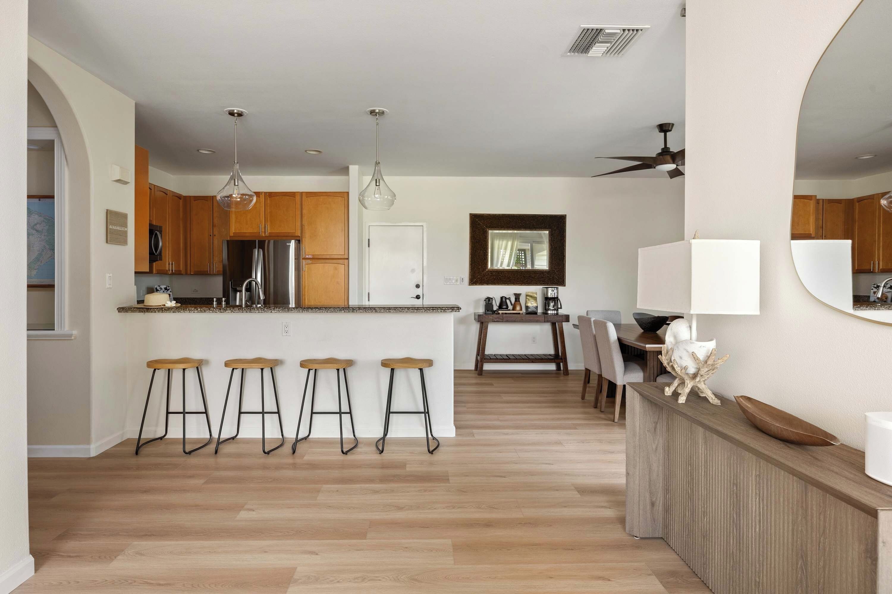 Une cuisine moderne avec des meubles en bois, un réfrigérateur en acier inoxydable et un coin bar avec des tabourets.