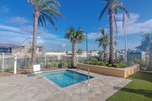 A swimming pool with a metal ladder, surrounded by palm trees and a white fence. - Easy Breezy with Gulf Views and walk to Pier Park (Panama City Beach)