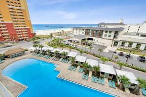 Un hôtel doté d’une piscine, offrant une vue sur la plage et avec une jetée en arrière-plan.
