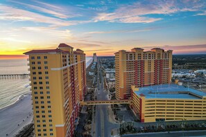 A high-rise hotel with multiple floors, a parking garage, and a view of the ocean at sunset. - Easy Breezy with Gulf Views and walk to Pier Park (Panama City Beach)