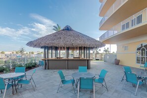 An outdoor seating area with a thatched umbrella, metal chairs, and a bar counter. - Easy Breezy with Gulf Views and walk to Pier Park (Panama City Beach)