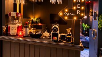 A bar area with a sign indicating it's open, a bottle of hot water, a candle, and various bar tools.