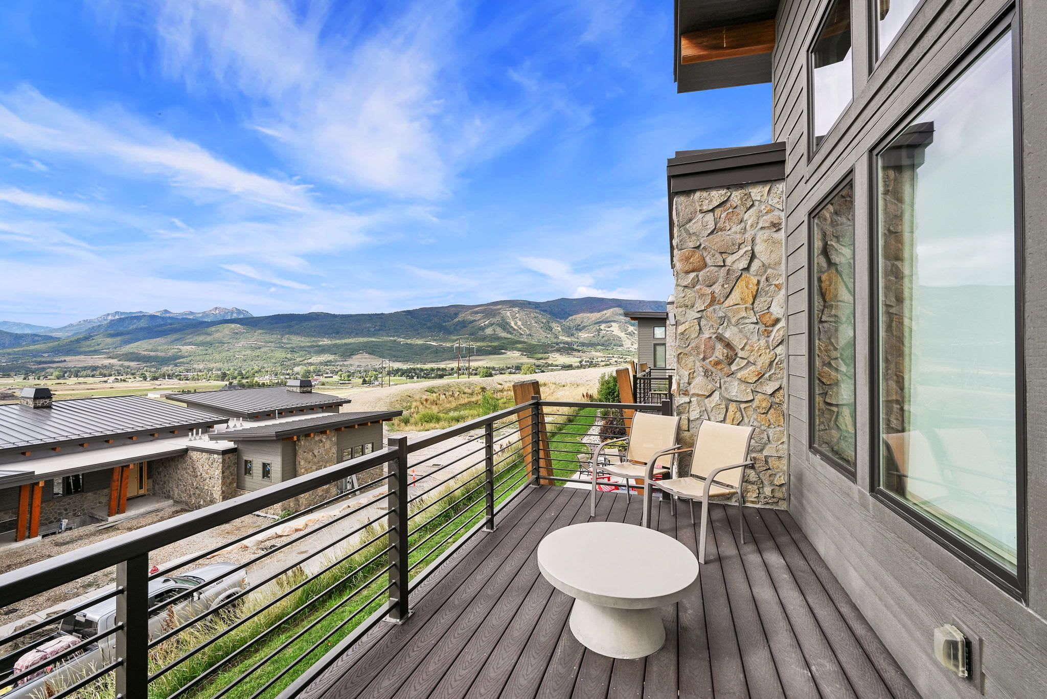 A balcony with a table and chairs, overlooking a mountainous landscape.