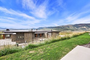 A modern house with a stone facade, large windows, and a view of rolling hills. - Stunning Townhome Mountain Views and Amenities (Eden)