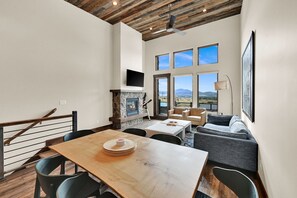 Uma sala de estar ampla com lareira, mesa de jantar e sofá.