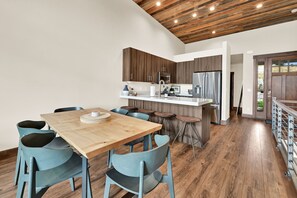 A modern kitchen with wooden cabinets, a stainless steel refrigerator, and a bar area with stools. - Stunning Townhome Mountain Views and Amenities (Eden)