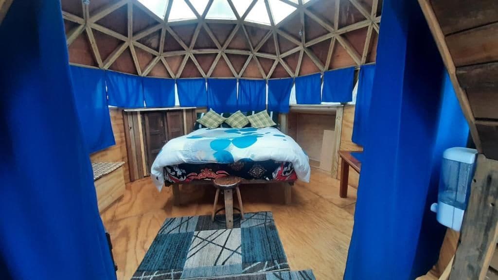 Een ronde kamer met een bed, een kruk en een kleine tafel.