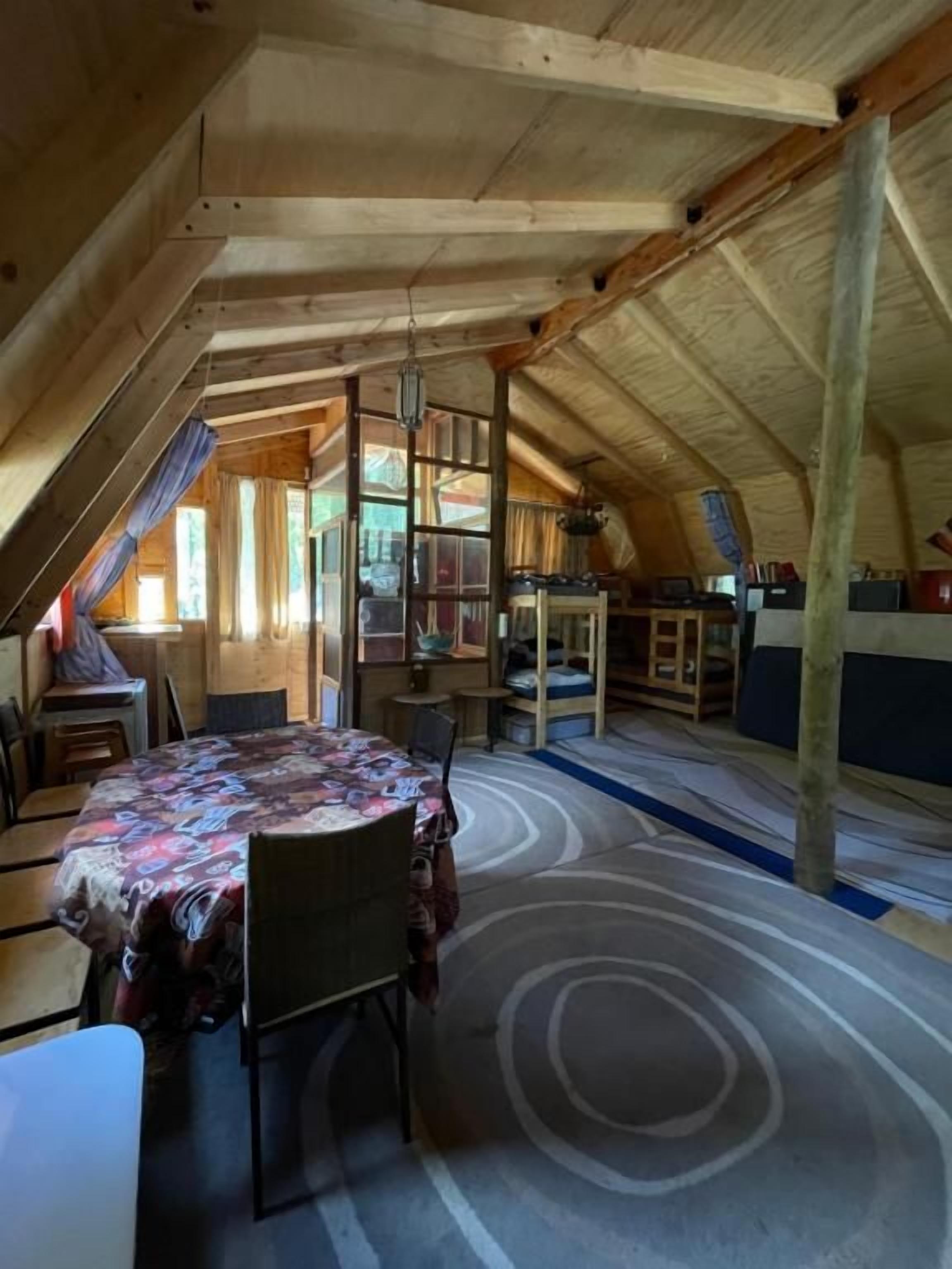 Une pièce mansardée comprenant une table à manger, des chaises et un tapis à motifs.