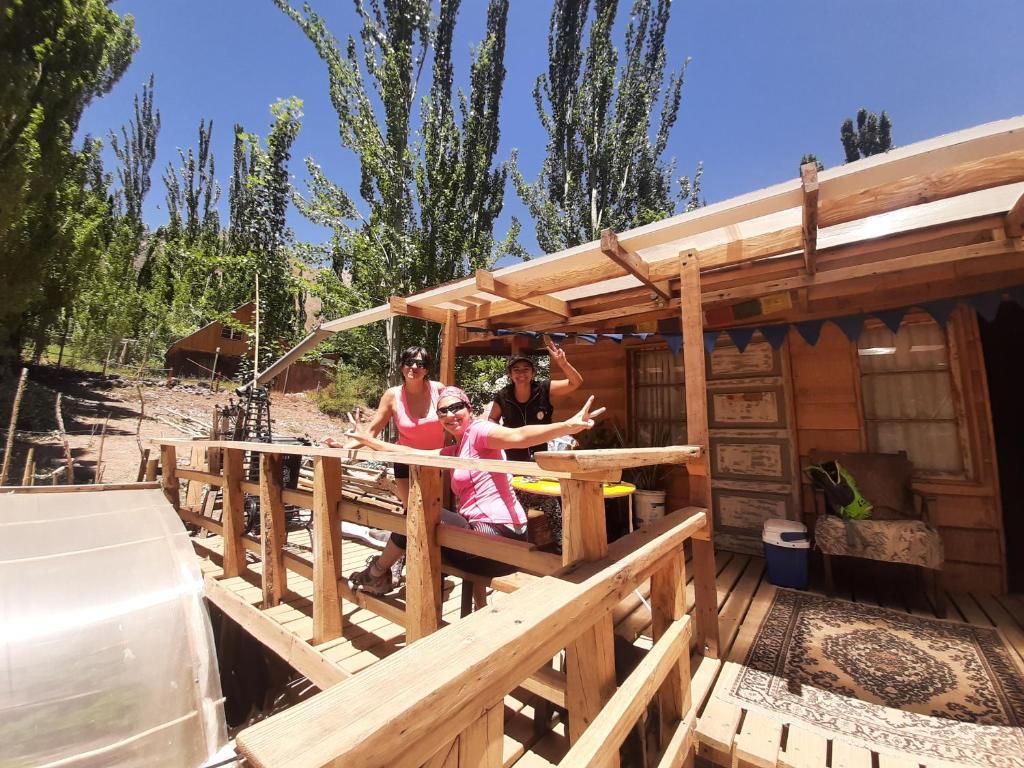 Una terraza de madera con un área de estar techada y un pequeño edificio con techo inclinado.