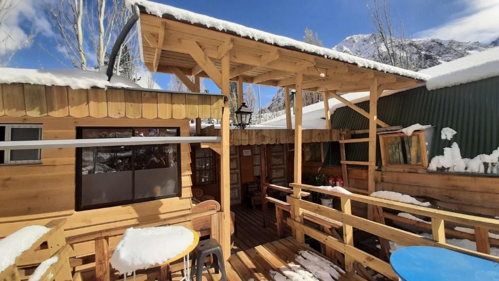 Une cabane en bois dotée d’un patio couvert, de tables et de bancs en bois.