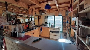 Una cocina rústica con armarios de madera, una estufa y diversos utensilios de cocina.
