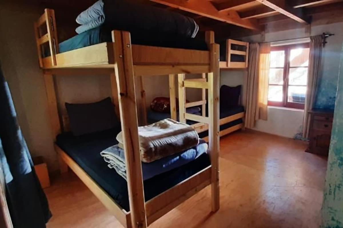 Een kamer met stapelbedden, een raam met gordijnen en een houten vloer.