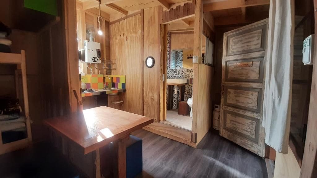 Un intérieur en bois comprenant une table à manger, un évier et une porte donnant sur une autre pièce.