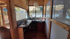 A compact kitchen with a gas stove, sink, and a hanging light fixture.