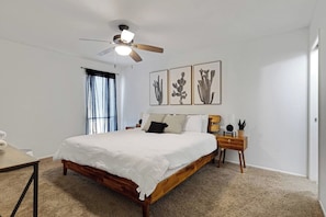 A bedroom with a wooden bed, a ceiling fan, a bedside table with a lamp, and framed artwork on the wall. - Private Pool, Patio TV, 15-min to Old Town (Phoenix)