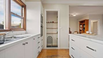 A modern kitchen with white cabinetry, a wooden floor, and a window.