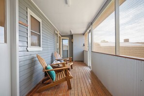 A covered porch with wooden chairs and a view of the beach. - Quinn House A Honey Home (Dubbo)