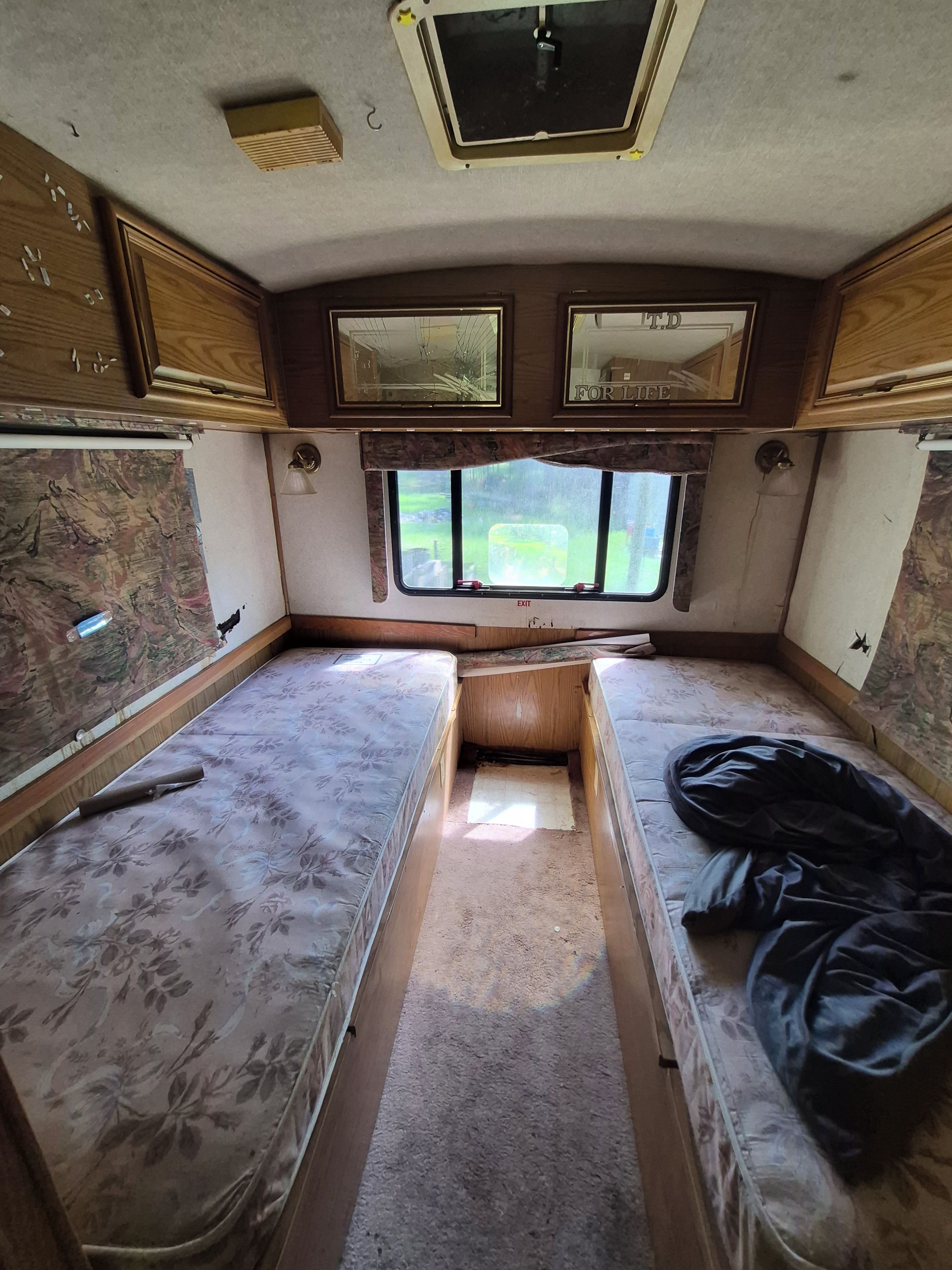 Ein kompaktes Wohnmobil-Interieur mit einer Küchenzeile, einem kleinen Fenster und einem zentralen Gang.