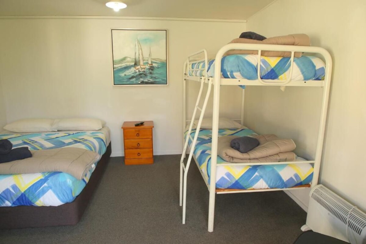 Una habitación con dos literas, un tocador pequeño, un cuadro en la pared y un radiador.