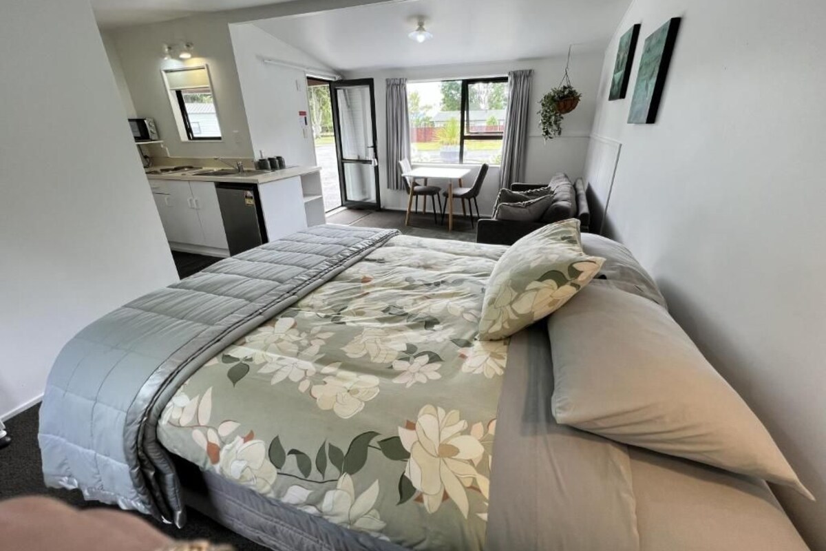 Un dormitorio con cama, una kitchenette pequeña y un comedor con mesa y sillas.