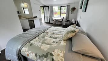 A bedroom with a bed, a small kitchenette, and a dining area with a table and chairs.