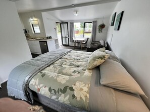 Un dormitorio con cama, una kitchenette pequeña y un comedor con mesa y sillas.