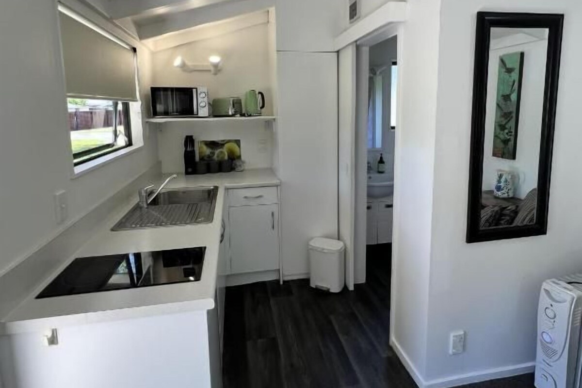 Cocina compacta con microondas, pileta y pequeño mostrador.