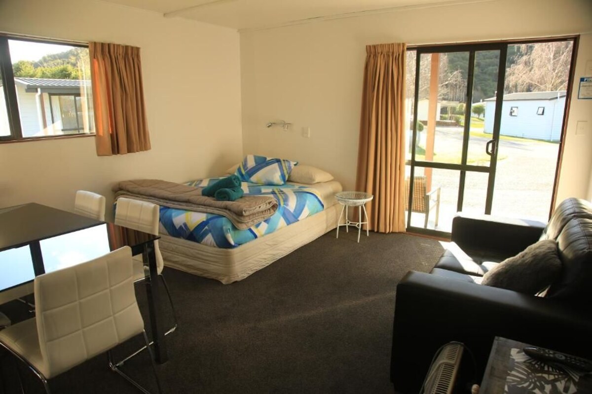 Una habitación con una cama, una mesita, una silla y un sofá.