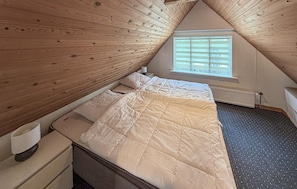 A bedroom with a sloped ceiling, a bed with white bedding, a window with blinds, and a radiator under the window. - Lovely home in Aabenraa with WiFi (Aabenraa)